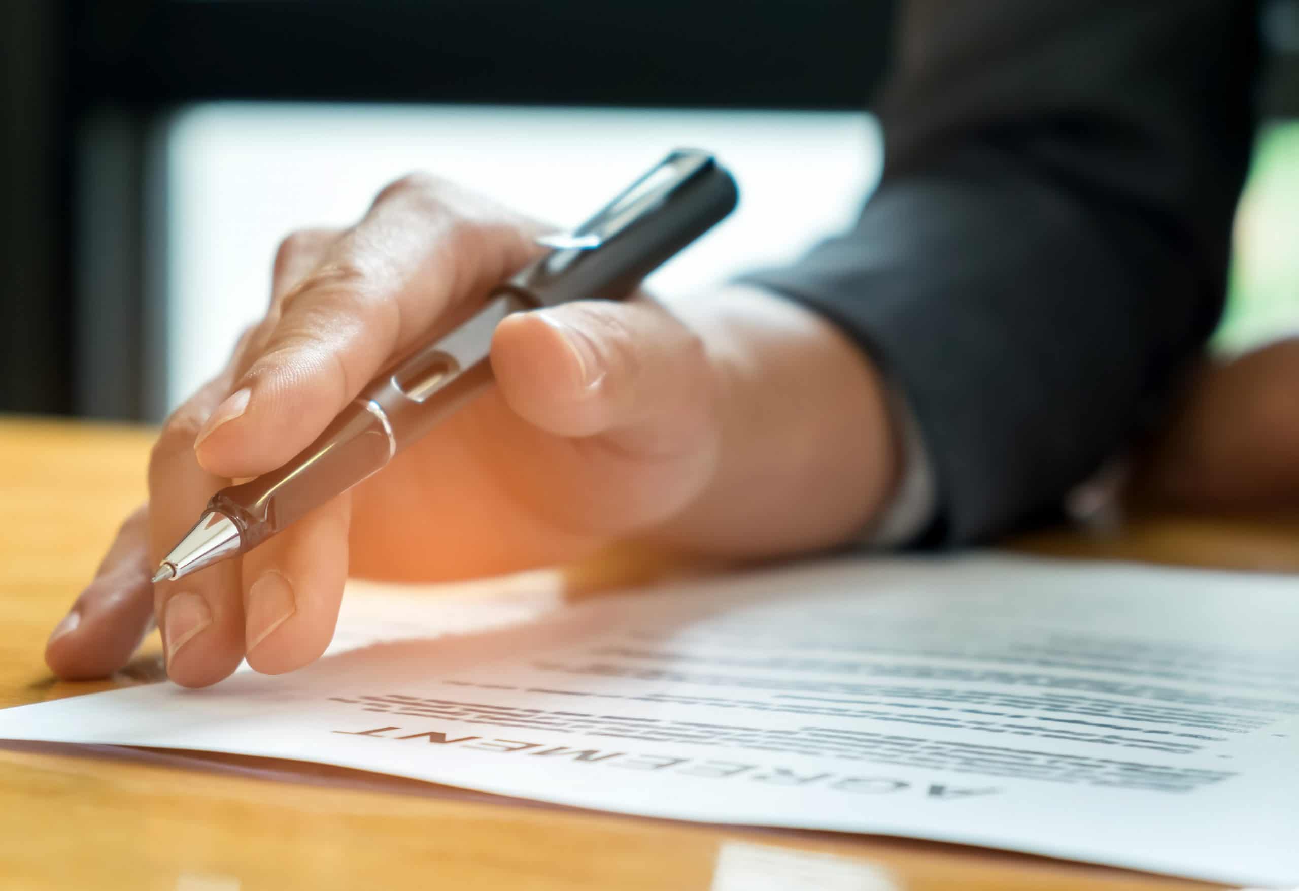 Homem segurando uma caneta e lendo um documento para simboilizar o entendimento do Certificado de Posto Revendedor da ANP