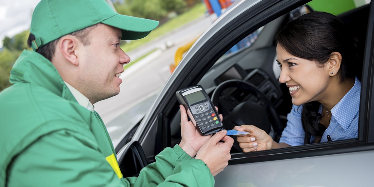 Vendedor segurando uma máquina de pagamento em cartão e seguindo um script de vendas para prestar um atendimento de qualidade ao cliente em um posto.