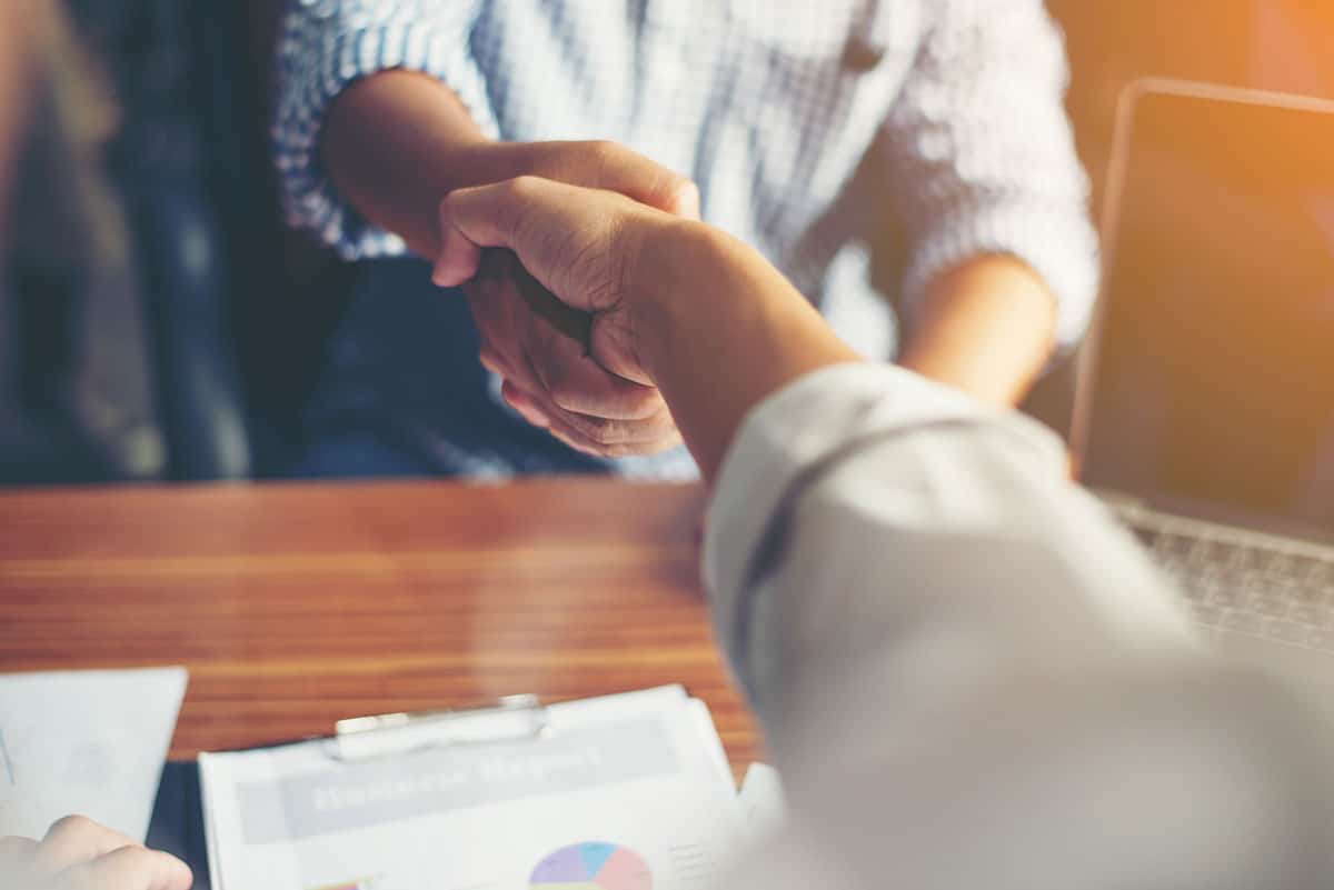 Dois empresários apertando as mãos para simbolizar a importância da parceria no comércio local.