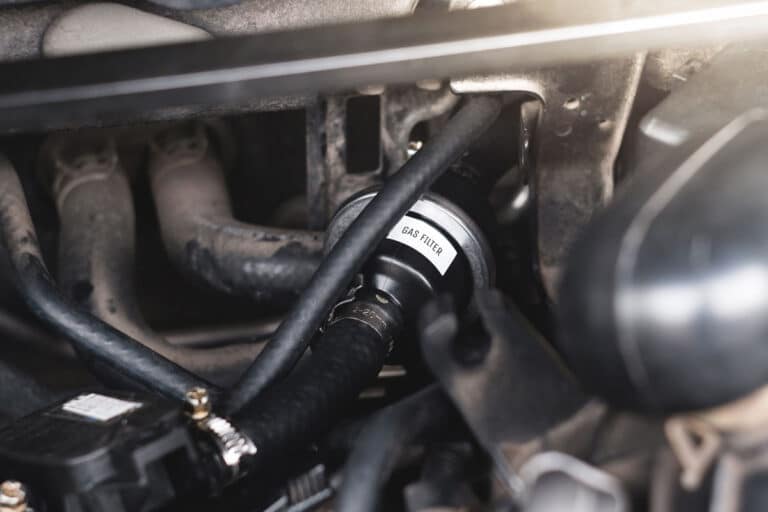 Mangueira de abastecimento GNV conectada a um carro adaptado para receber o combustível.